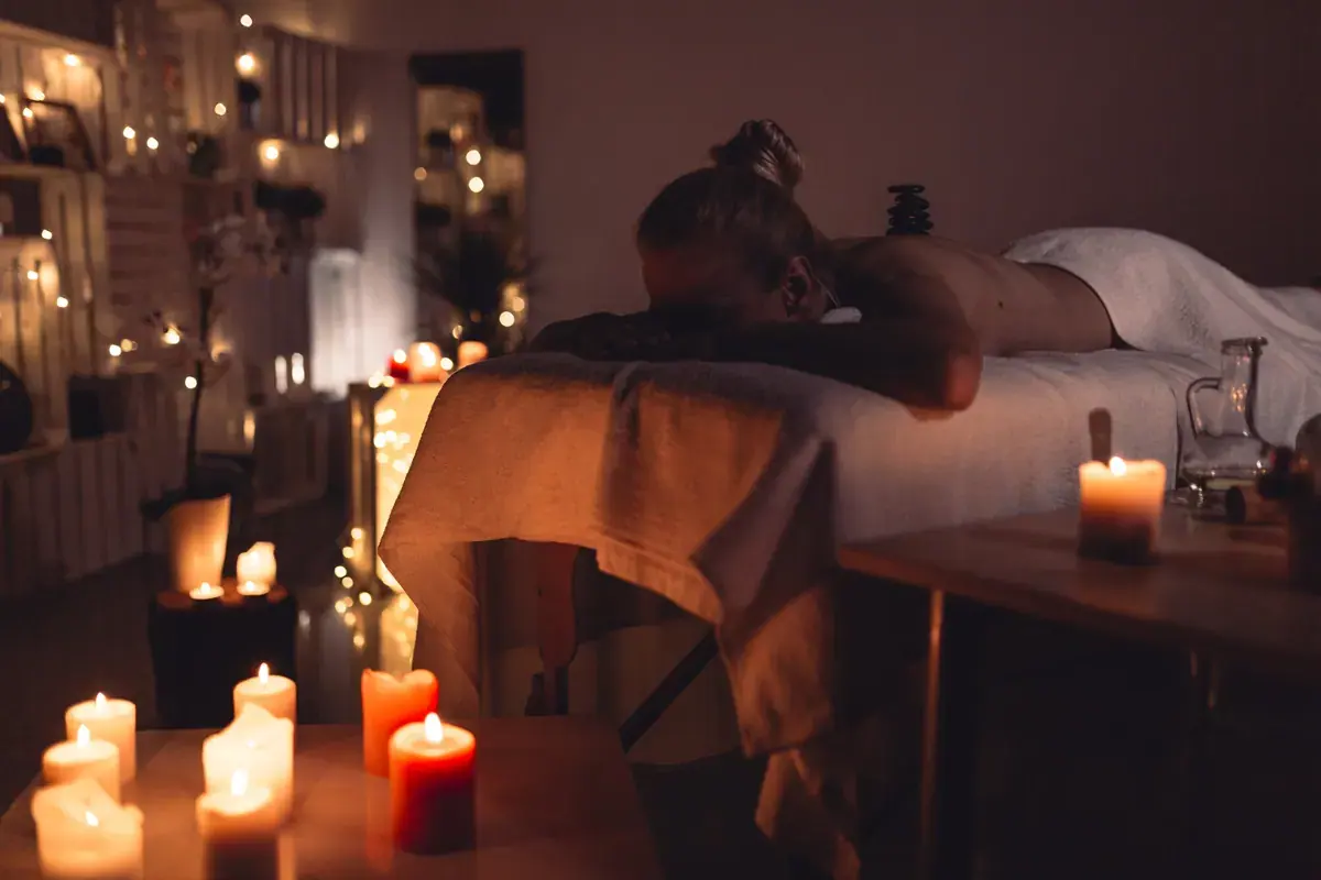 Candlelit massage room at Aimi Bangkok Massage with a guest lying face down on a treatment table under warm string lights