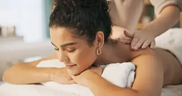 A woman lies relaxed with her eyes closed while a therapist massages her shoulders at Andheri Massage in Mumbai