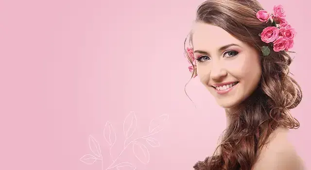 Smiling woman with wavy brown hair decorated with pink roses against a soft pink background, for Angel Spa in Mumbai