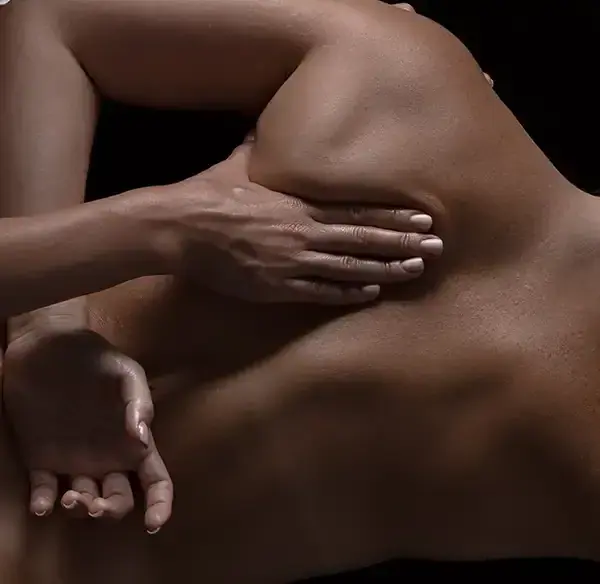 Close-up of a person's bare back and shoulder with one hand resting on it, for Angels Touch Massage in London