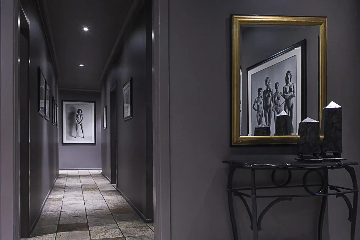 Dimly lit hallway with stone floor and framed black-and-white art at Bellevue 5 Star Retreat in Sydney