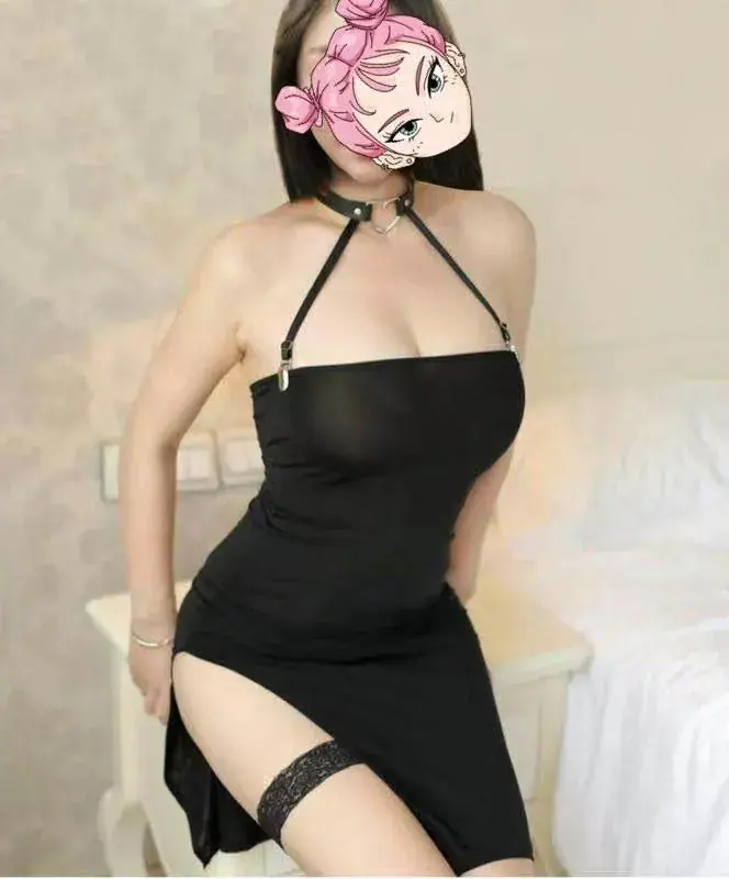 Woman in a black halter dress with a choker posing beside a bed at CBD 378 Elite Massage in Sydney