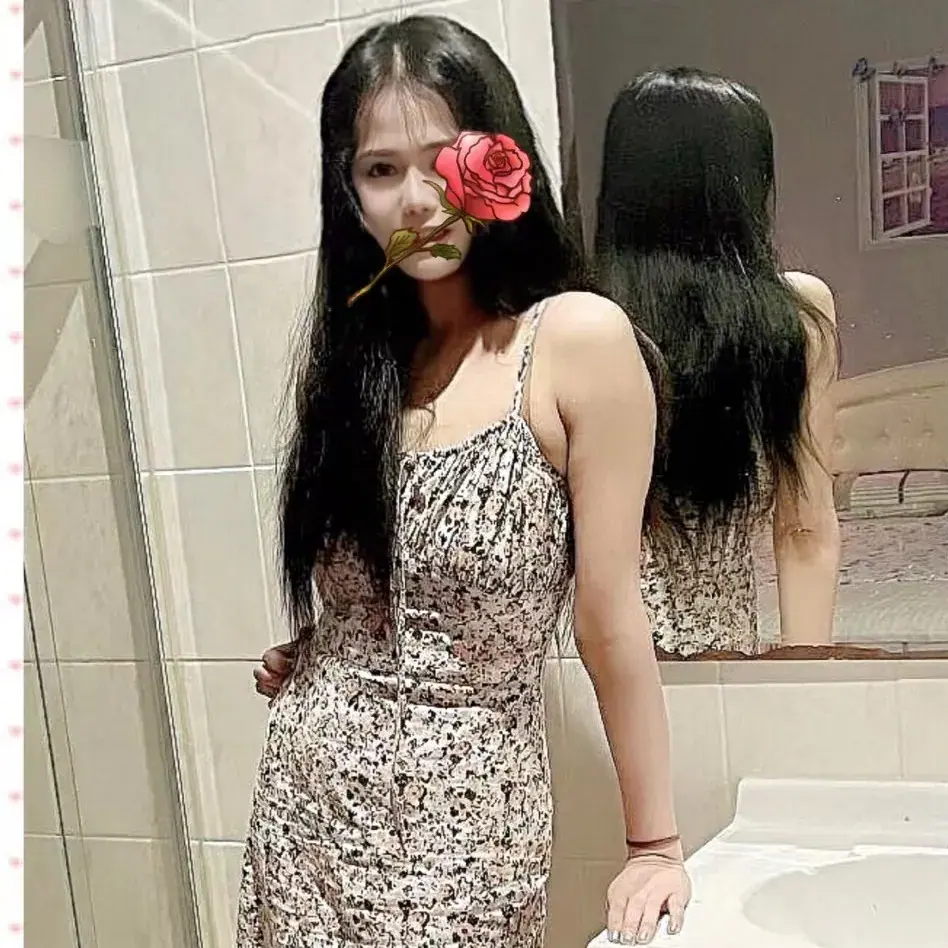 A woman with long dark hair in a floral sundress poses in a tiled bathroom at CBD 378 Elite Massage, Sydney
