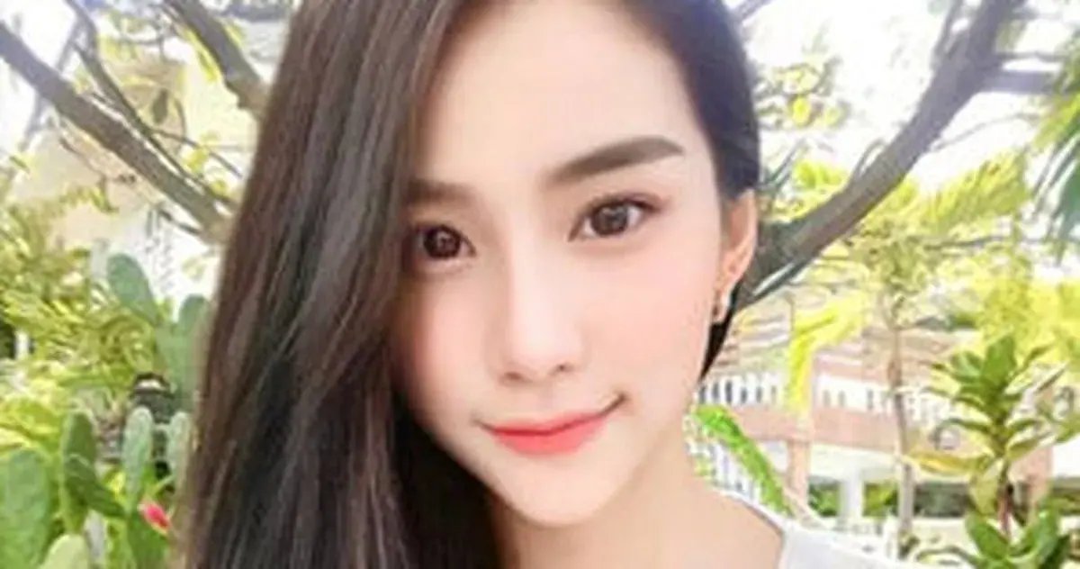 Close-up selfie of a smiling young woman with long dark hair outdoors among tropical plants, for Don Quixote Nuru Massage