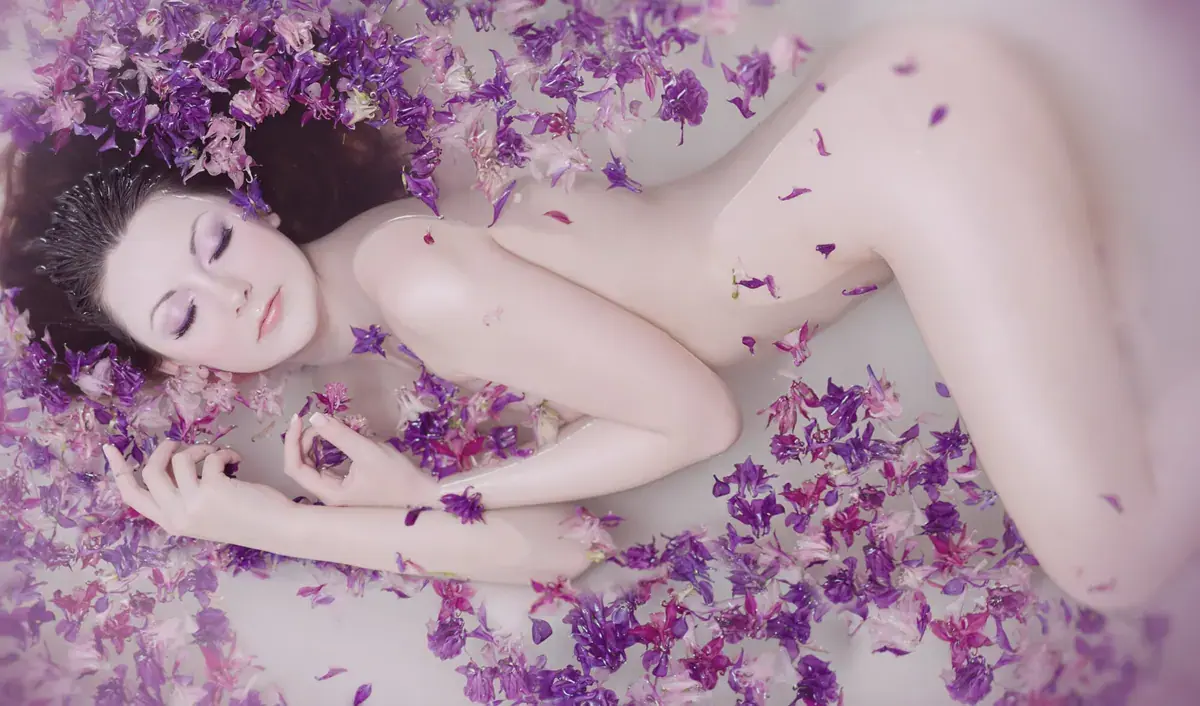 Woman lying in a bath covered in purple flower petals at Dream Girl Massage in Sydney