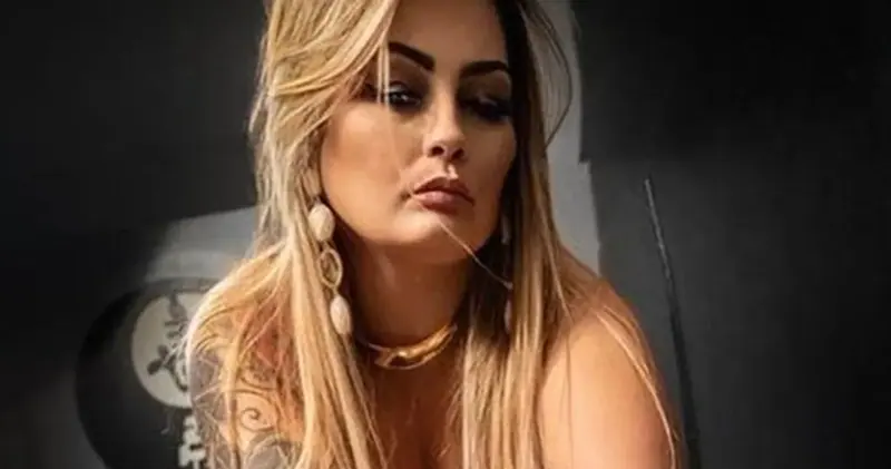 Woman with long blonde hair, gold drop earrings and a gold choker poses for a portrait at Eros Massagens in Rio de Janeiro