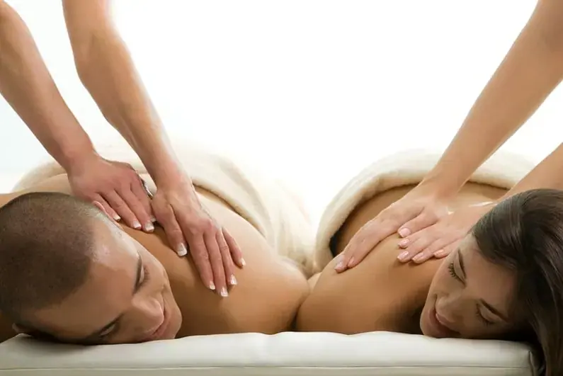 A couple lying side by side on a massage table receiving back massages at Erotic massage salon Eden in Moscow