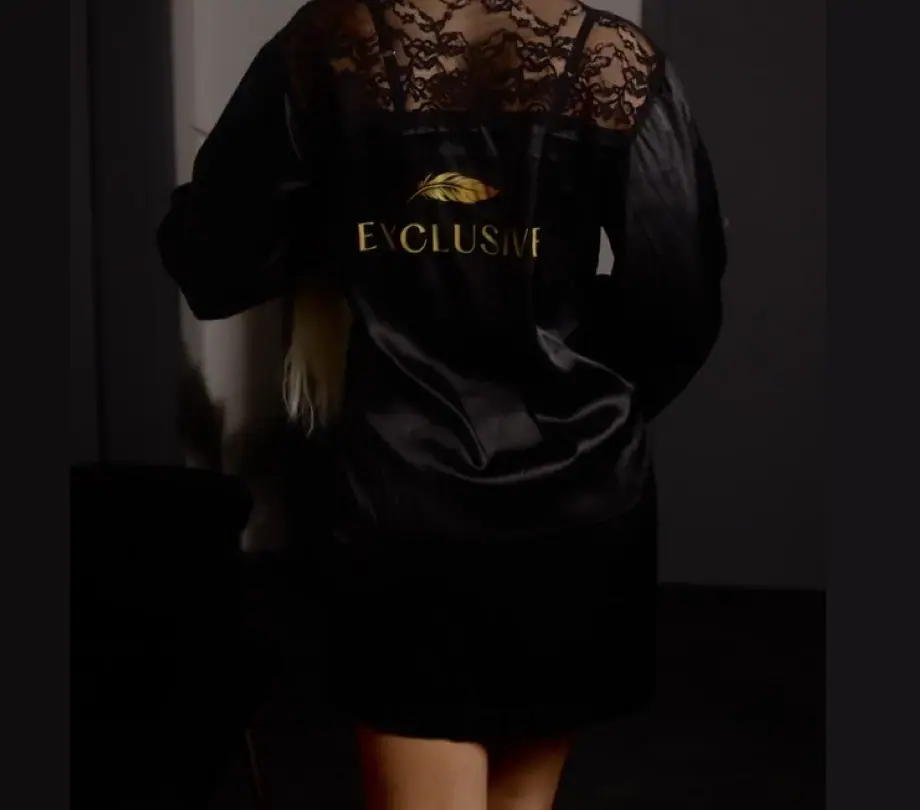 Woman seen from behind in a black satin robe with lace shoulders, photographed in dim light for Exclusive Brno Tantra