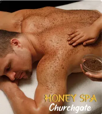 A shirtless man lies face down while a therapist applies an exfoliating scrub to his back at Honey Spa in Mumbai