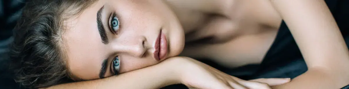 Close-up portrait of a blue-eyed woman resting her head on her arm, used for Je Vous Sydney erotic massage salon in Sydney