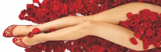 Woman's legs in red strappy sandals resting on a bed of red rose petals, for Ladies Massage in Moscow