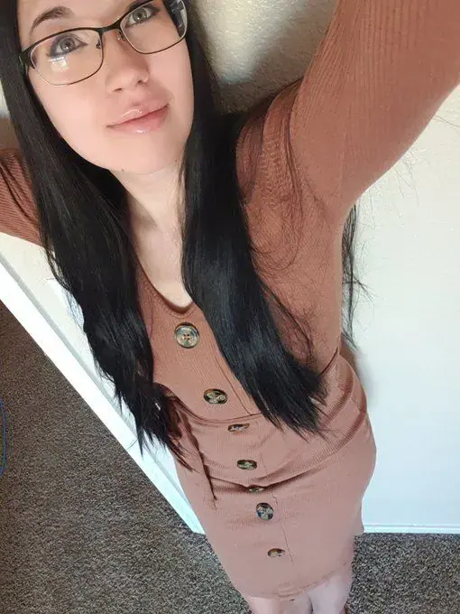 Woman with long dark hair and glasses in a rust-colored buttoned dress takes a selfie for Leilalovesexy in Prague