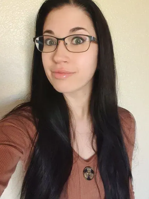 Selfie of a smiling woman with long dark hair and glasses in a rust-colored top, for Leilalovesexy in Prague