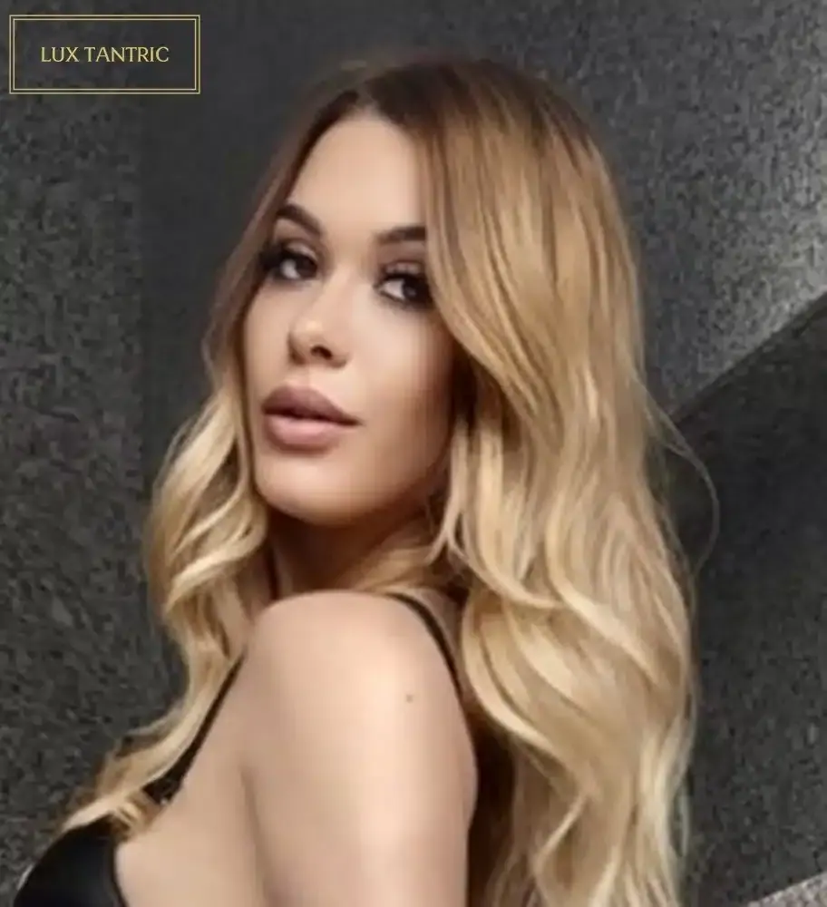 Portrait of a woman with long wavy blonde hair looking over her shoulder, used for Lux Tantric in London