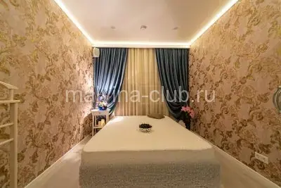 Massage room at Mal'vina Klub in Moscow with a padded table, ornate gold wallpaper and blue curtains