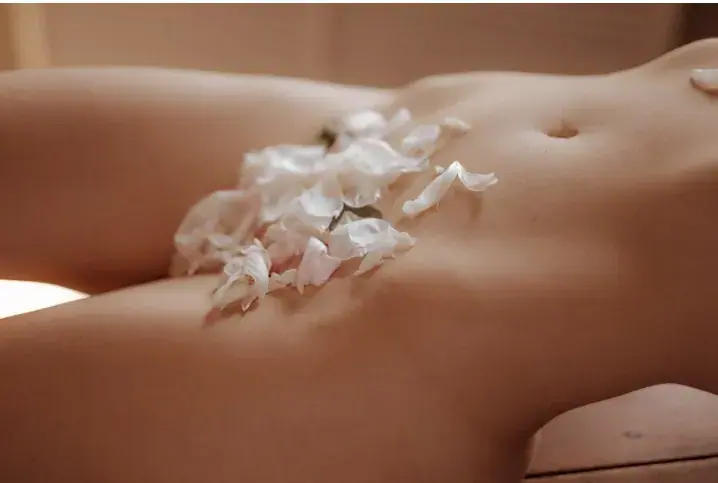 Close-up of white flower petals resting on a reclining person's bare torso, used as an image for Massage Good in Kyiv