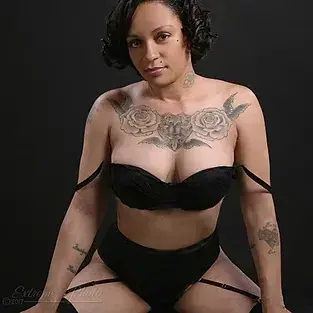 Studio portrait of a woman with short dark curls and chest tattoos, wearing black lingerie, for MidWest Charlee in Las Vegas