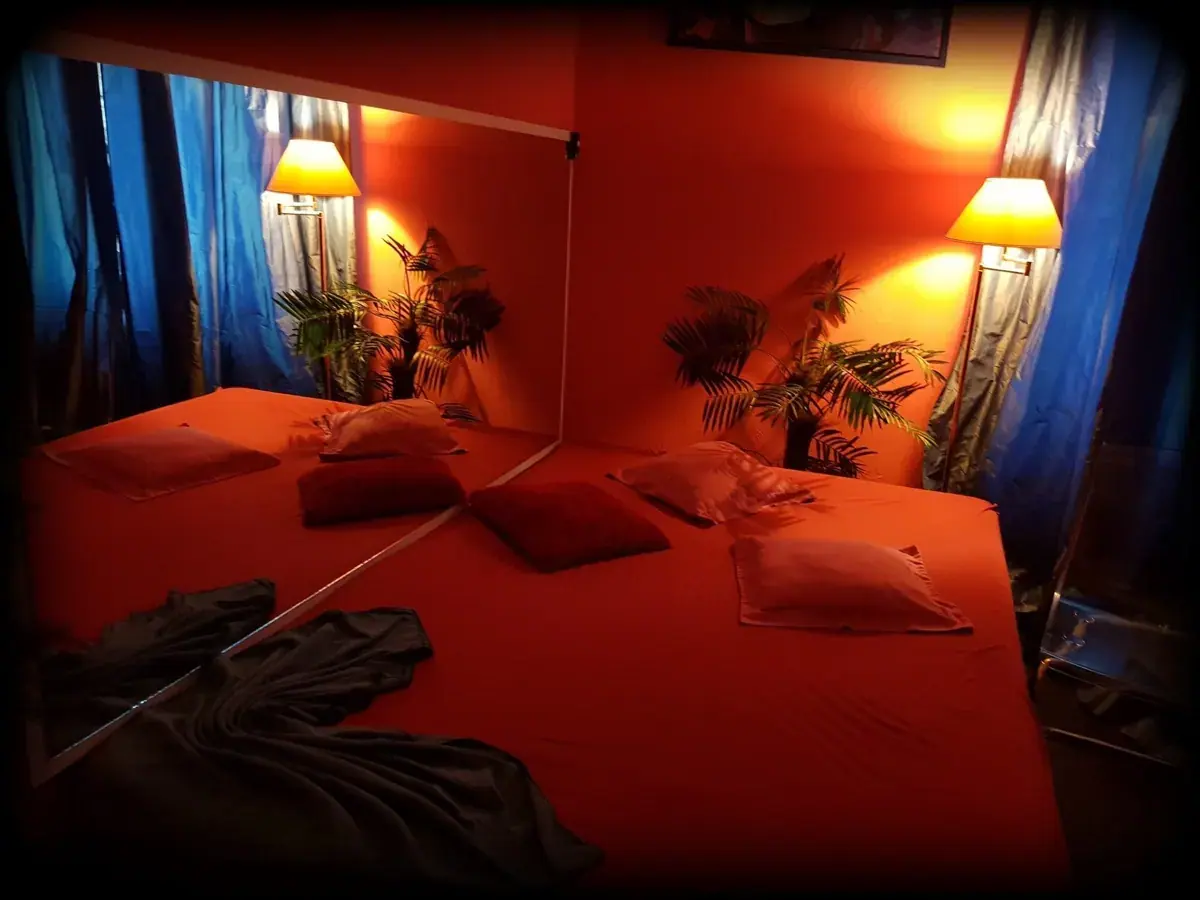 Red mattress bed with large mirror and warm lighting at Mona Roses in Berlin