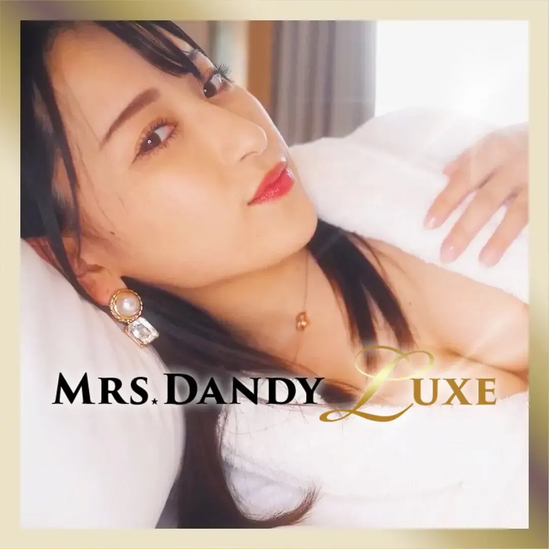 A woman with long dark hair and red lipstick reclines against white pillows in a promotional photo for Mrs Dandy in Tokyo