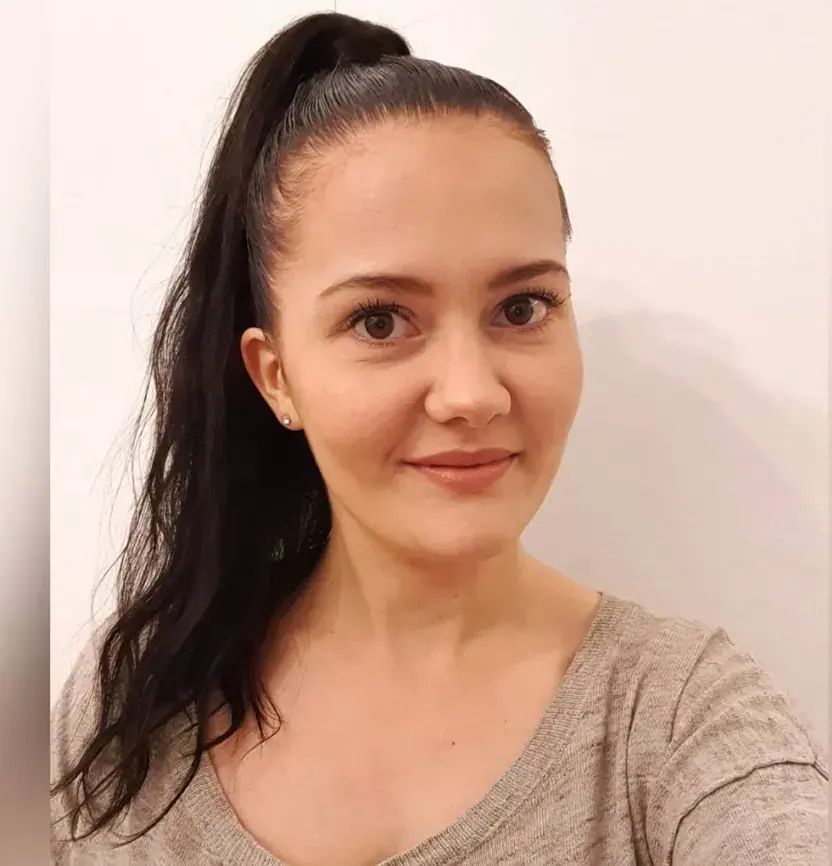 Selfie-style portrait of a smiling woman with a long dark ponytail, wearing a beige top, for Nicolekaminski in Warsaw