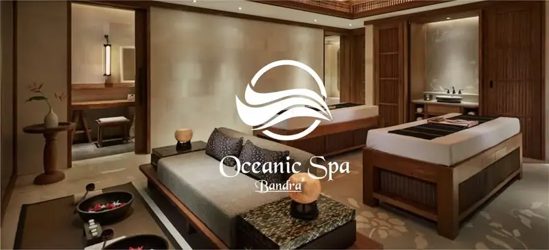 Dimly lit spa treatment room with two massage beds, a daybed and wood paneling at Oceanic Spa in Mumbai