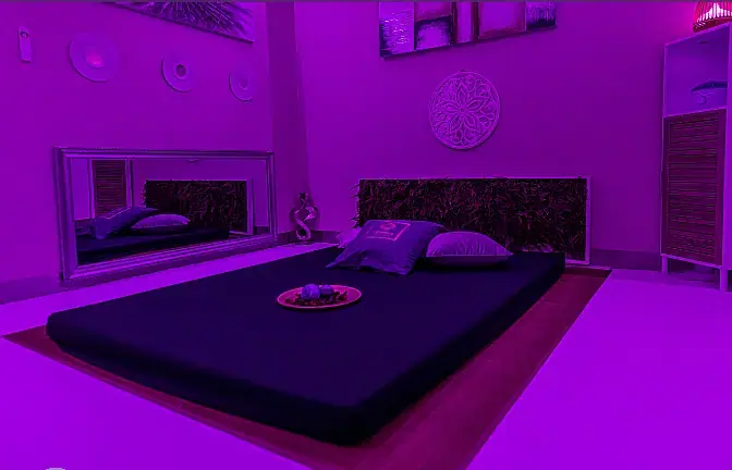 Purple-lit treatment room at Paradise Lisbon SPA in Lisbon with a low floor mattress, cushions and a large wall mirror