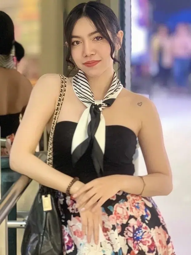 Woman in a black strapless top, striped neckscarf and floral skirt posing indoors, Picasso Bkk, Bangkok