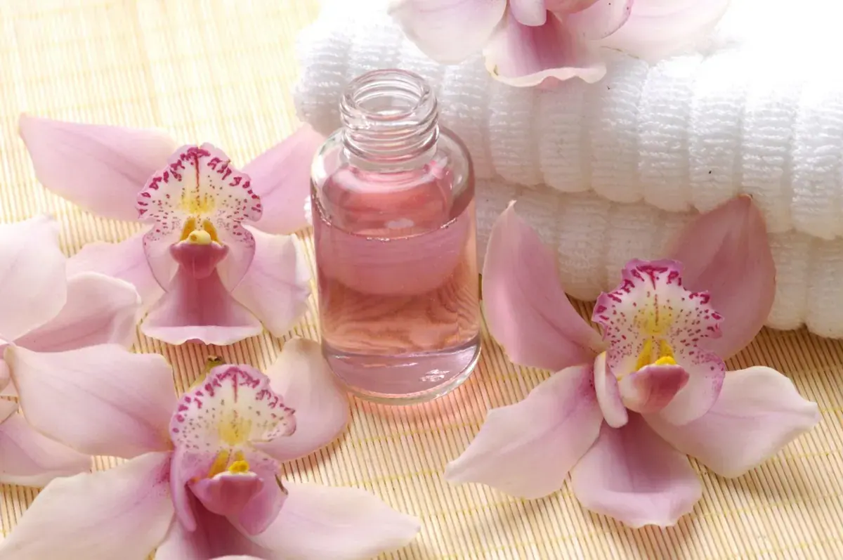 Pink orchids, a small bottle of massage oil and folded white towels on a bamboo mat at Real Promiscuous Massage Sydne in