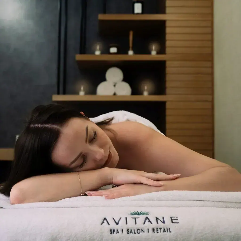 A relaxed woman lies on a massage table in a candlelit treatment room, shown for Royal Spa Andheri in Mumbai