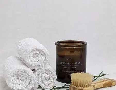 Rolled white towels beside an amber scented candle and a wooden bristle brush, as at Royal Spa Andheri in Mumbai