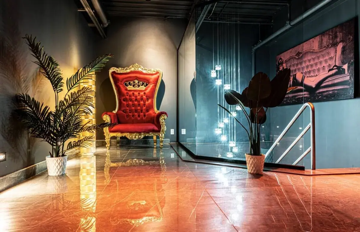 Ornate red and gold throne chair in a modern lounge with potted plants and glossy floors at Salon Lanternes Rouges, Montreal