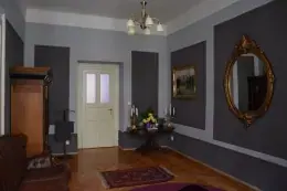 Elegant entrance hall at Salon VIP in Prague with gray walls, an ornate oval mirror, a wooden floor and a chandelier