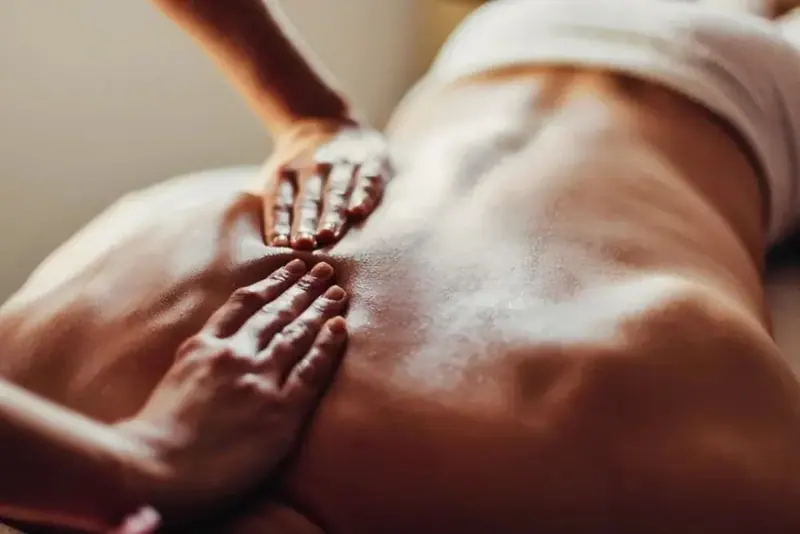 Close-up of a masseuse's hands working on a client's bare back at Smile Bangkak, a massage salon in Bangkok