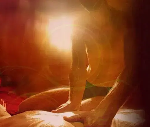 Warm, softly lit photo of a massage in progress at Tantra Templom in Budapest, with a person leaning over a client