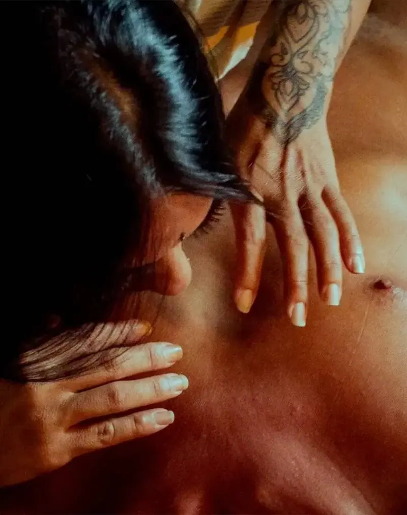Close-up of a woman with dark hair leaning over a bare-chested client during a massage at Tantra Zen in Lisbon