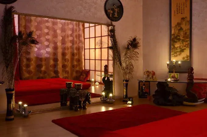 Candlelit room at Tao Erotic Massage in Bucharest with red floor mats, a large mirror and Asian-style decor