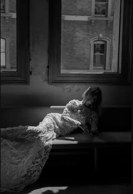 Woman in an elegant gown reclining by a window at The Gala Boudoir in Paris