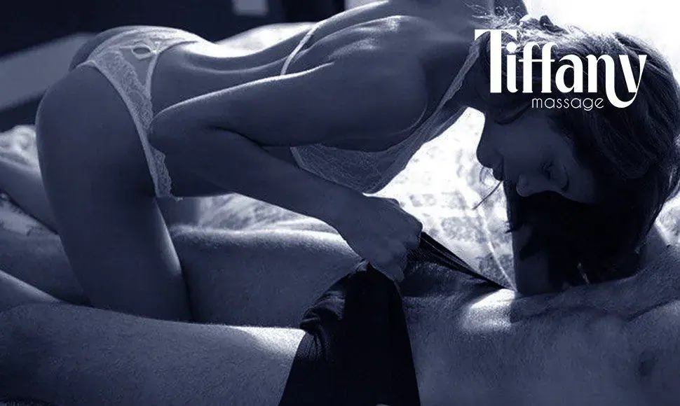 Black-and-white photo of a woman in lace lingerie leaning over a man on a bed, at Tiffany Massage in Prague