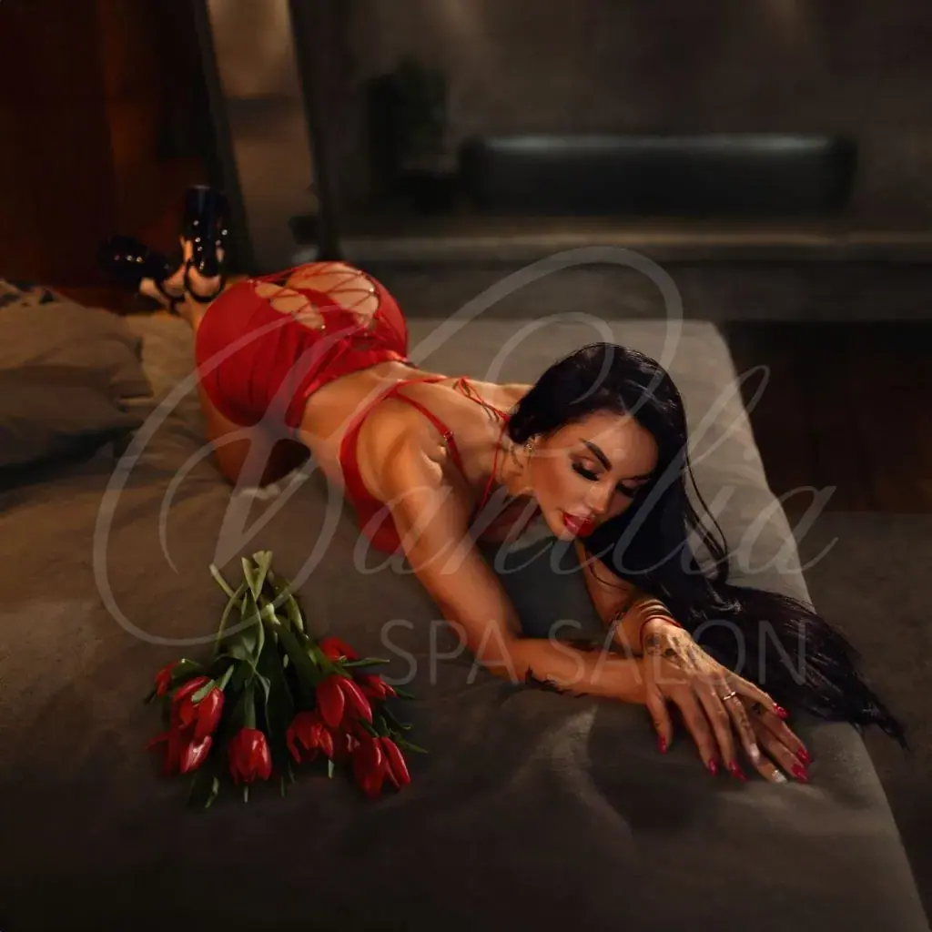 Woman in red lingerie and heels posing on a bed beside a bouquet of red tulips at Vanilia salon in Moscow